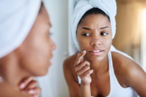 Woman frowning looking in the mirror before her anti-wrinkle fillers appointment