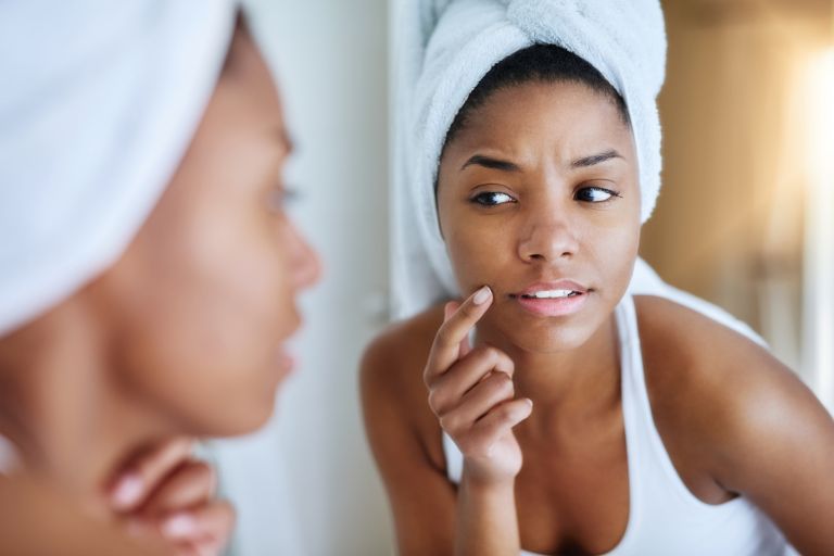 Woman frowning looking in the mirror before her fillers appointment