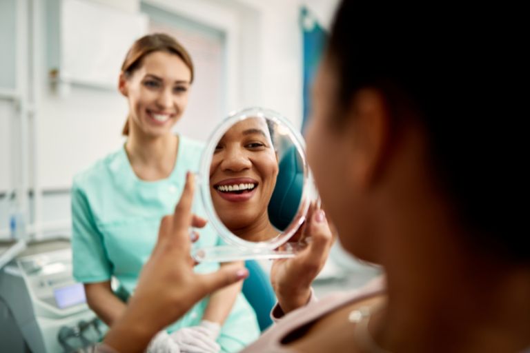 Woman smiling and looking at teeth in mirror